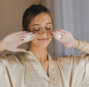 Rahulolev naine näo puhastamise ajal, hoiab peopesadel puhastusvahu tutsakaid.